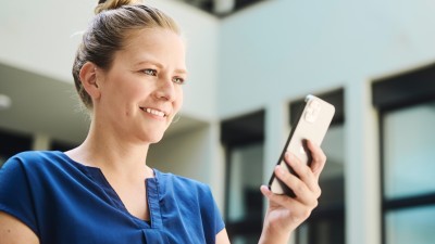 Smiling woman holding a smartphone in her hand.